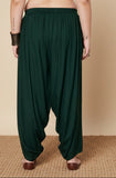 Woman wearing dark green harem pants on a beige background
