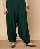 Woman wearing dark green harem pants on a beige background