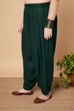 woman wearing dark green harem pants on a beige background