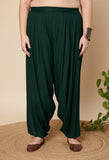 Woman wearing dark green cowl salwar pants on a beige background